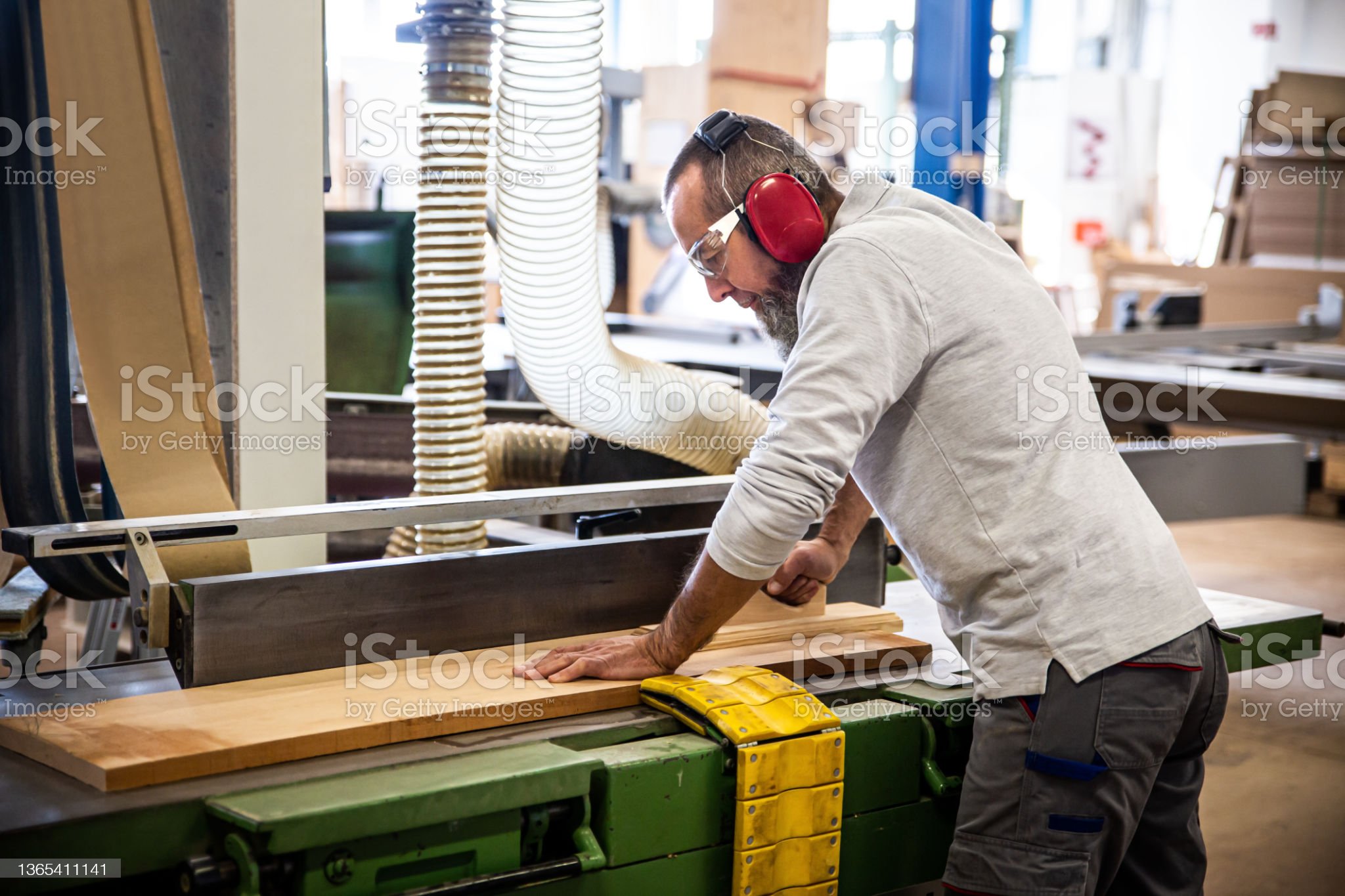 male craftman is working with a planer bench, worker is using a electric planer in a workshop or carpentry